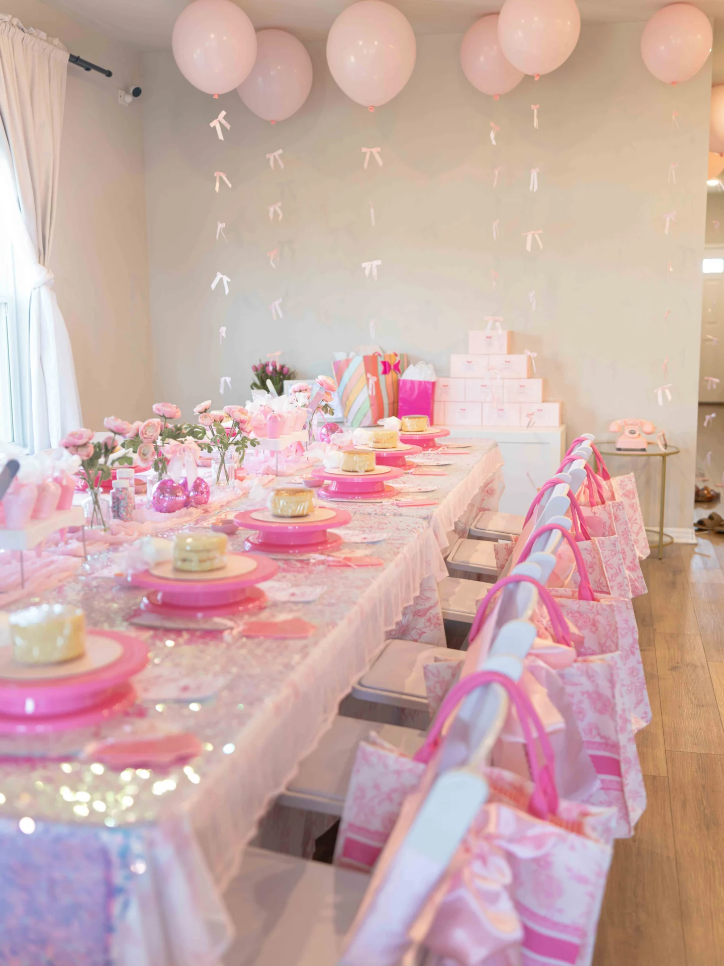 Pink-themed party table with balloons and gifts.