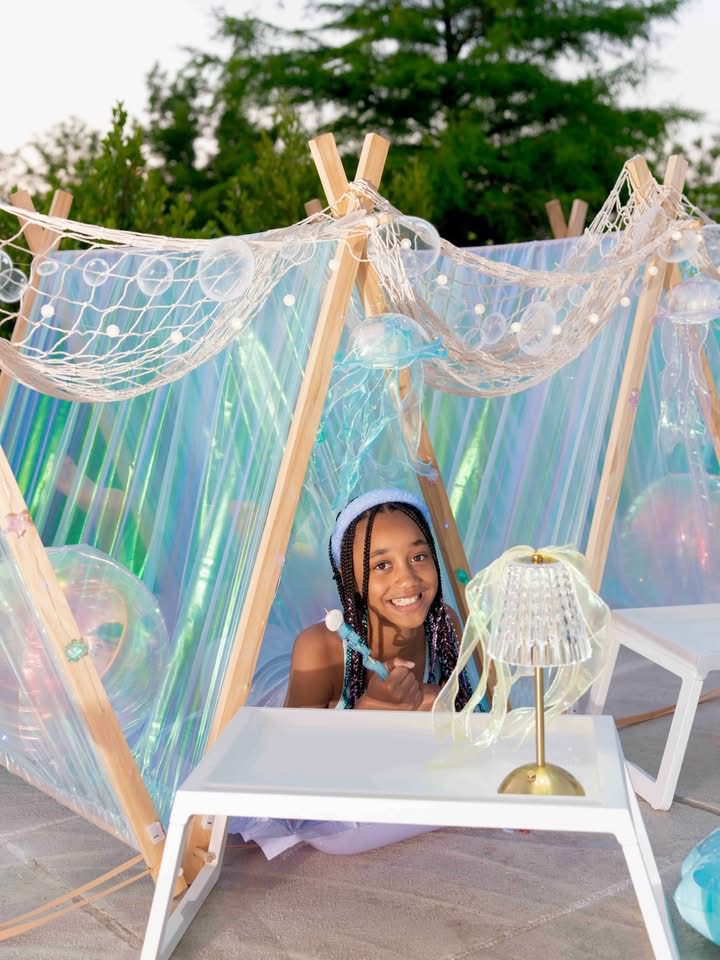 Child smiling in decorative outdoor tent.