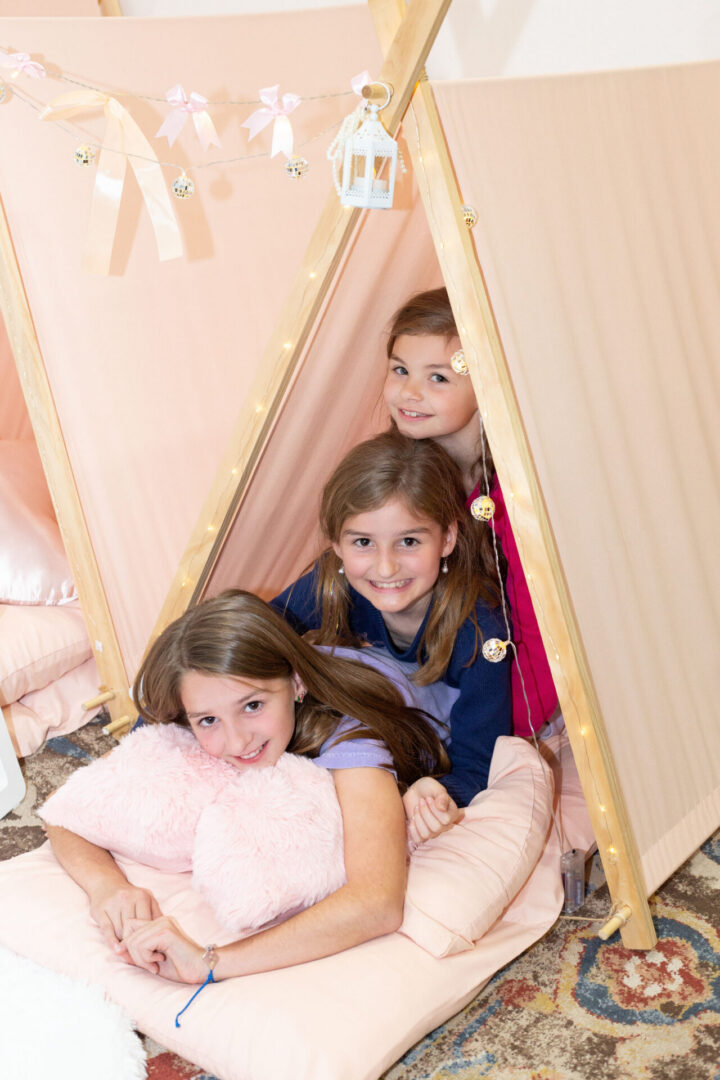 Three girls in a pink play tent.
