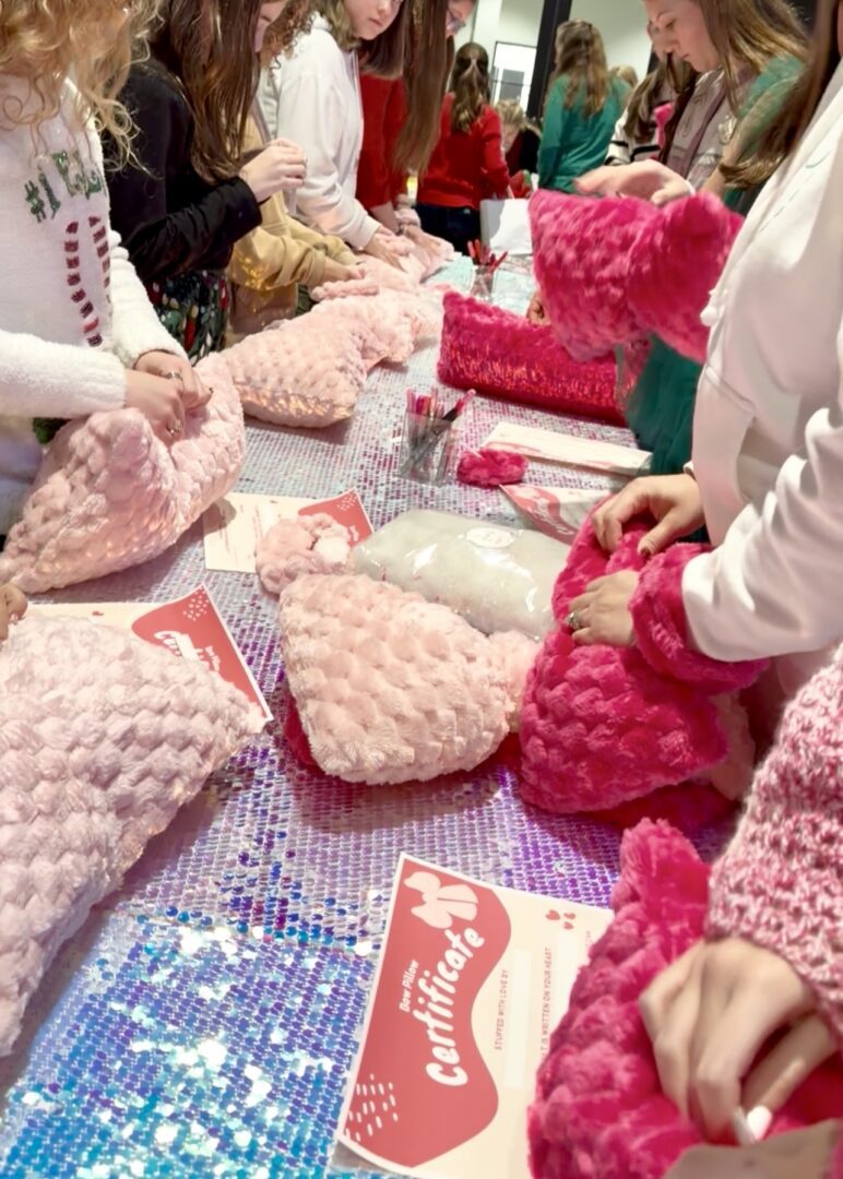 Children crafting with pink plush fabric.