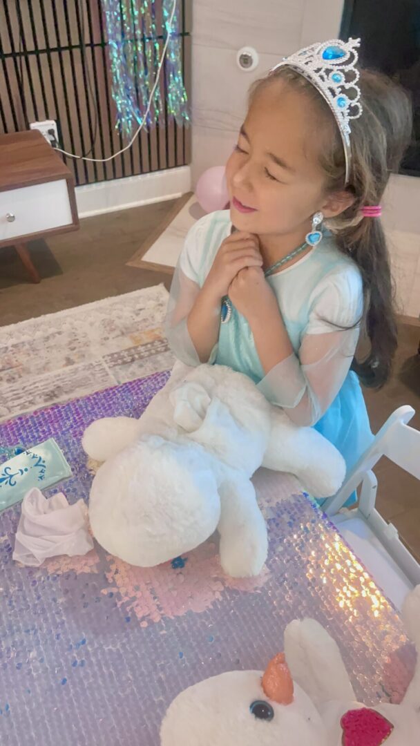 Girl in princess costume with stuffed toy.