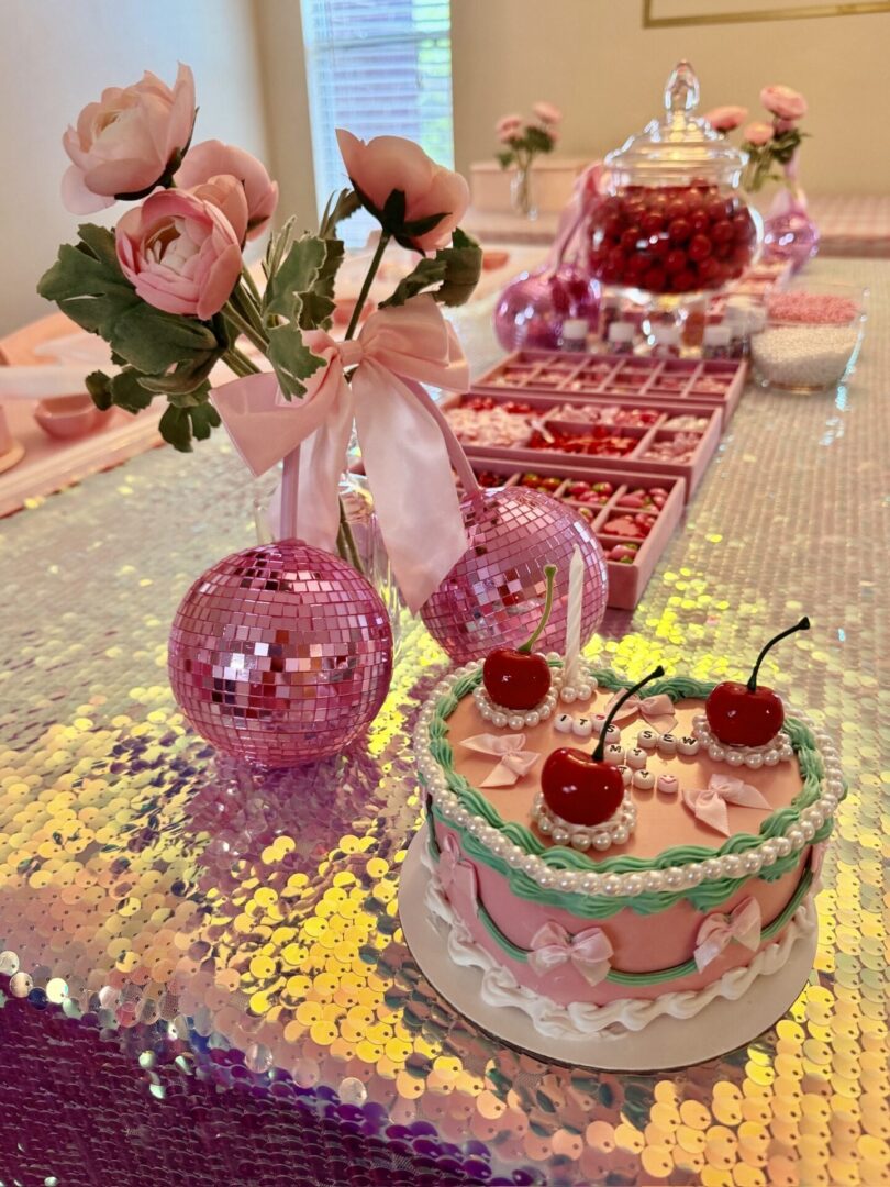 Pink-themed party table with cake and flowers.
