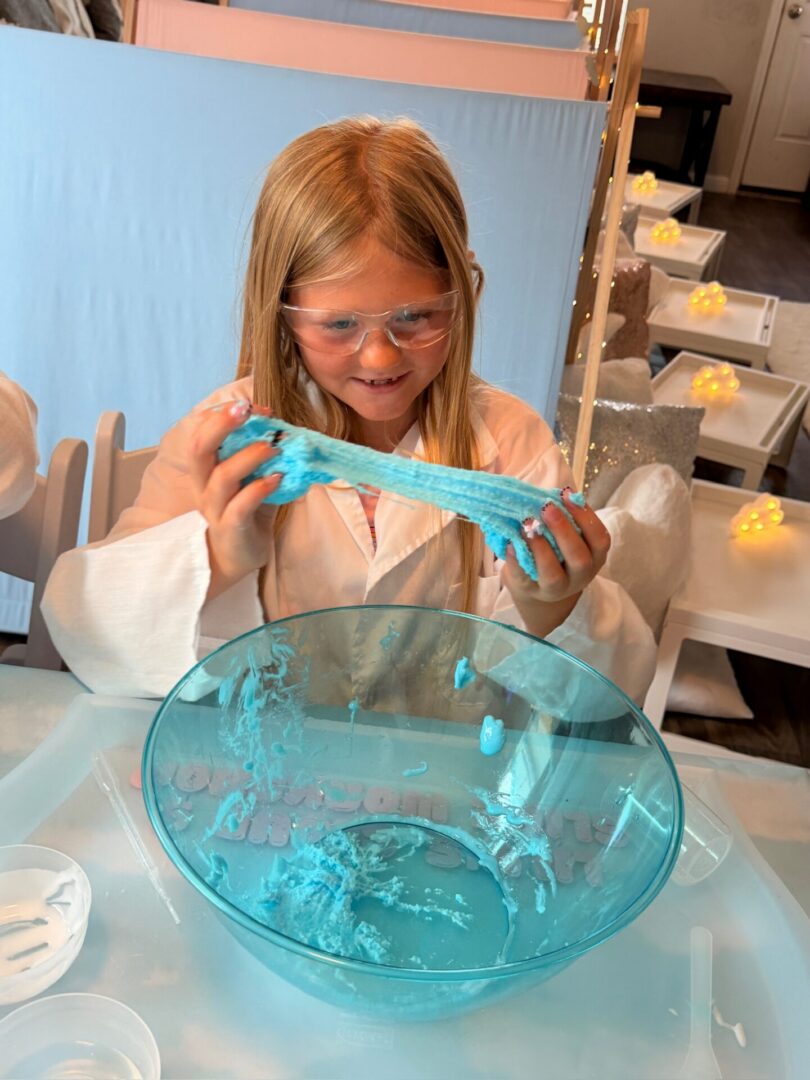 Child playing with blue slime in bowl.
