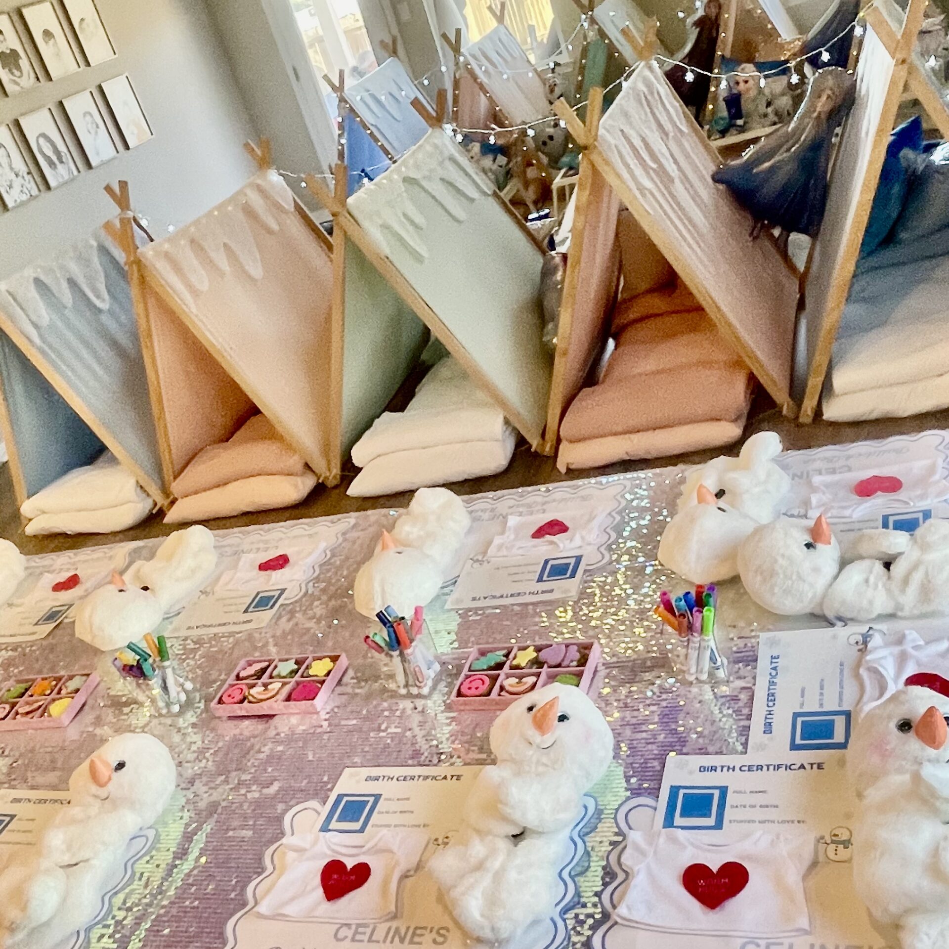 Table topped with lots of stuffed animals, papers, pens, boxes, and other objects