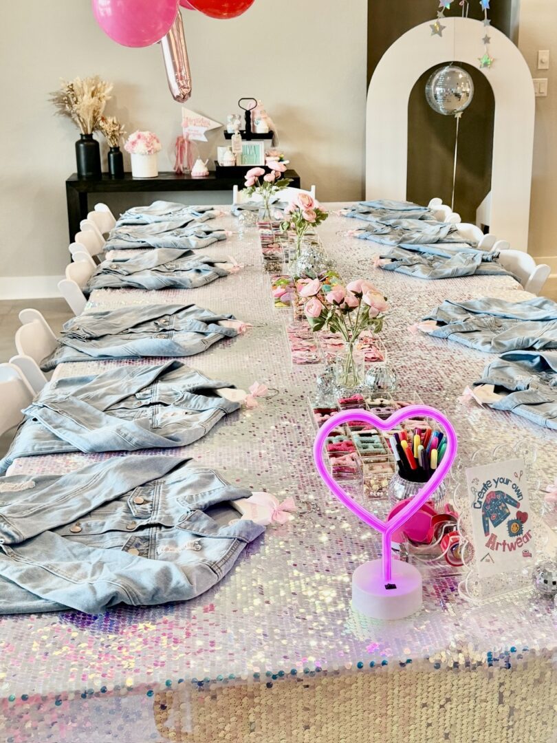 Table with a variety of items on it, including flower vases, clothes, pens in a stand, and other objects