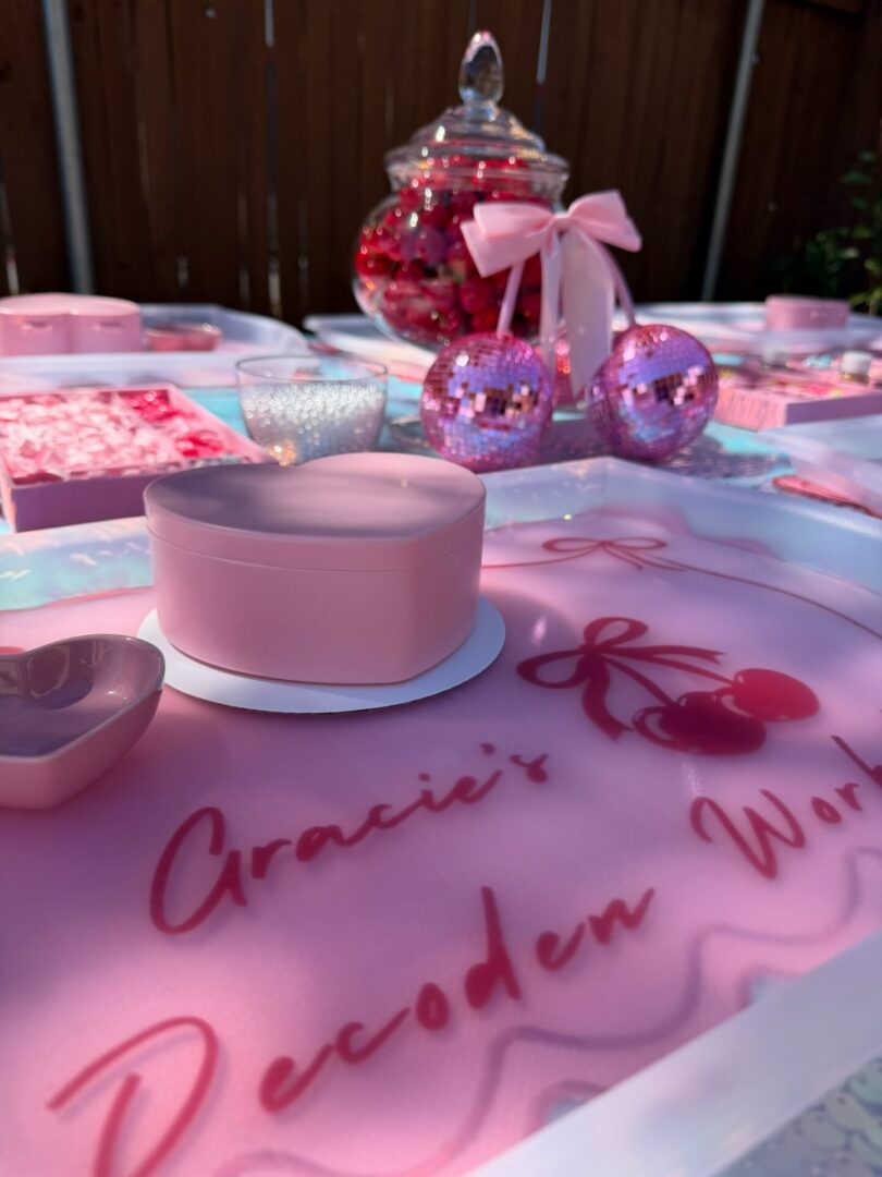 Table topped with lots of pink and white decorations, including a box, bowl, plate, and other objects
