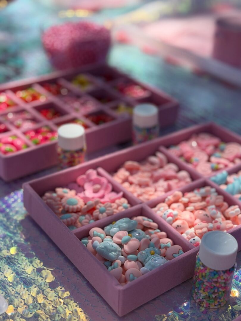 Table topped with lots of different types of candy, including boxes filled with colorful candies and bottles