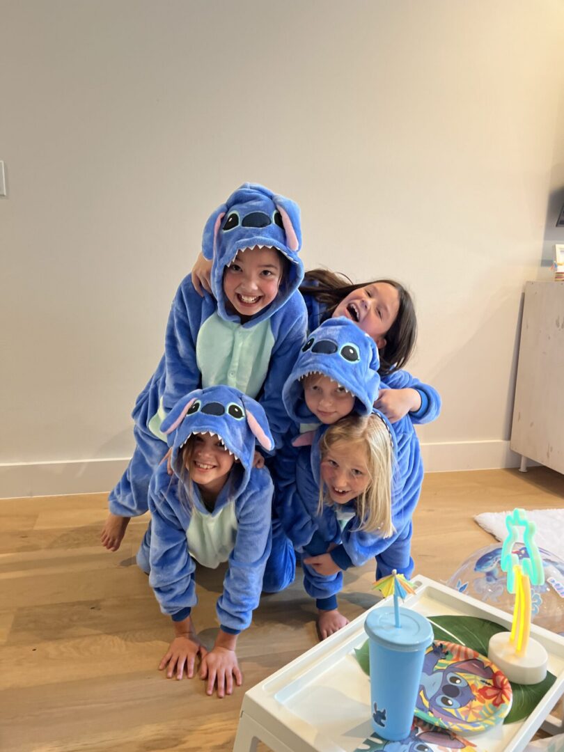 Children wearing blue Stitch onesies, smiling together.