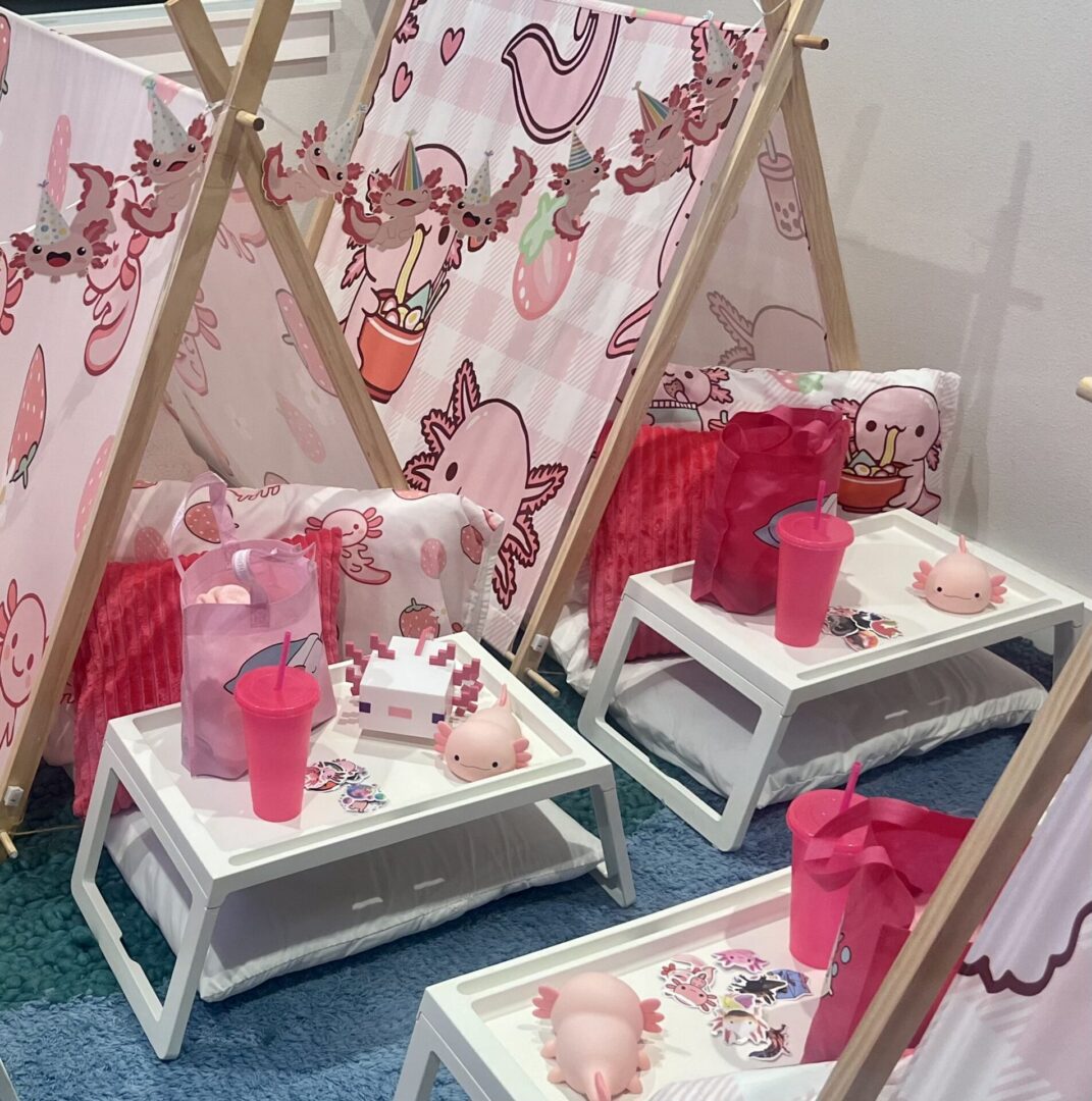 Pink-themed indoor tents with trays and drinks.