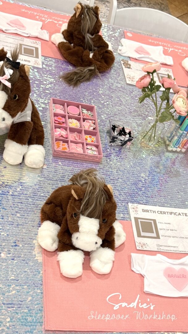 Stuffed horses on a glittery craft table.