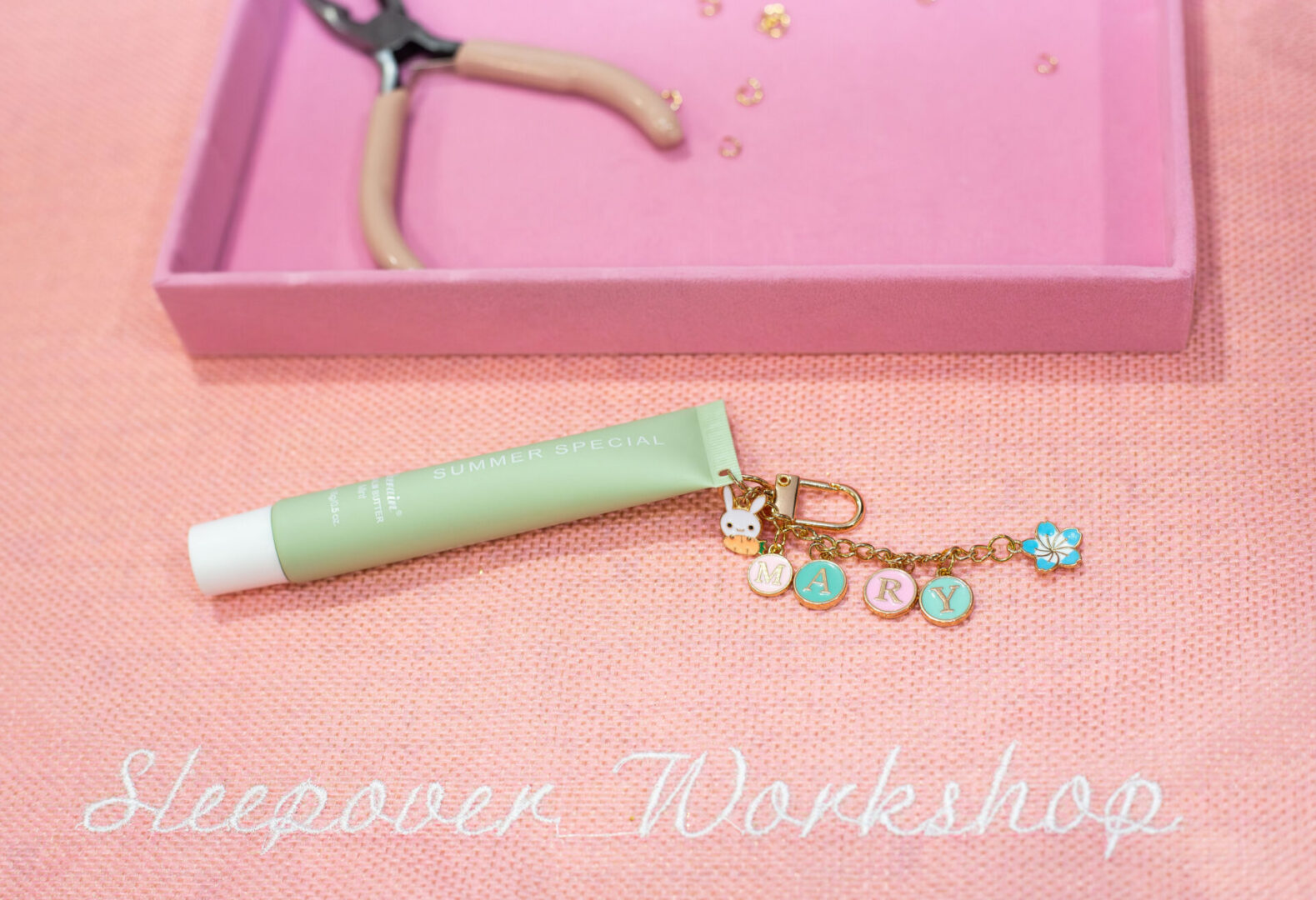 Craft supplies and keychain on pink surface.