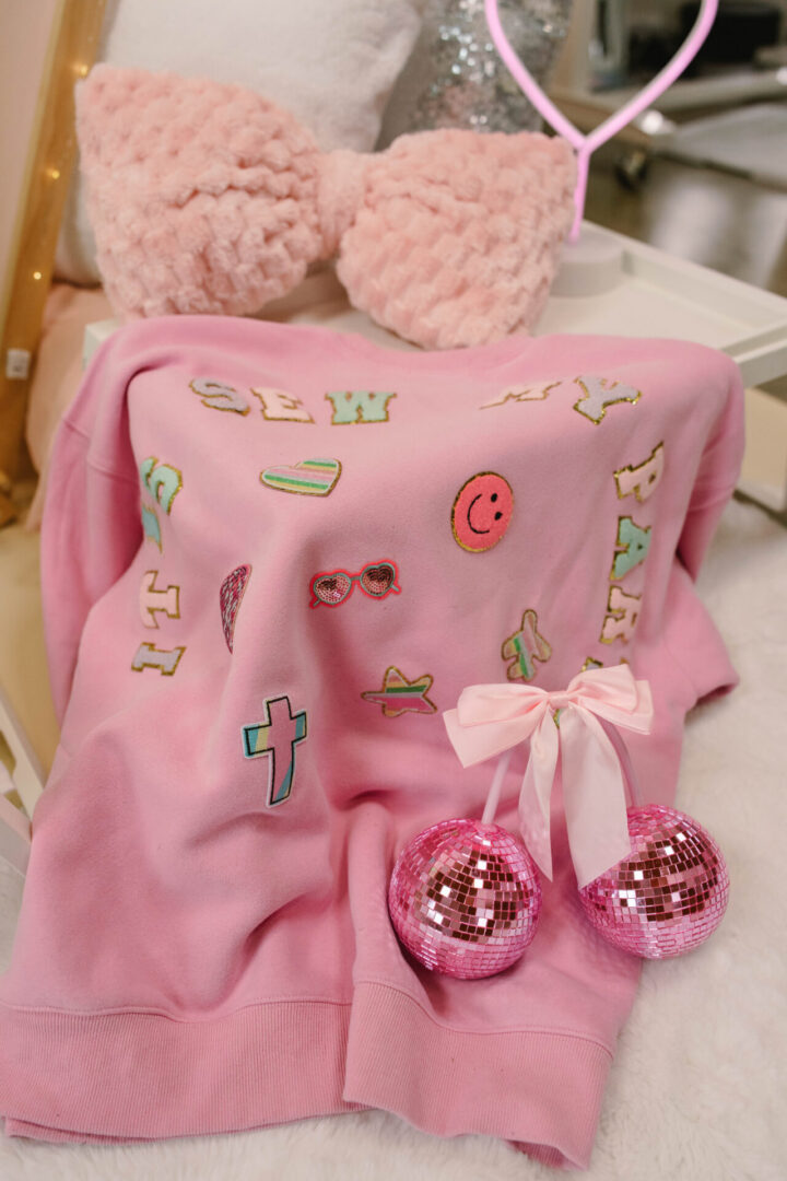 Pink sweater with playful designs and decorations.
