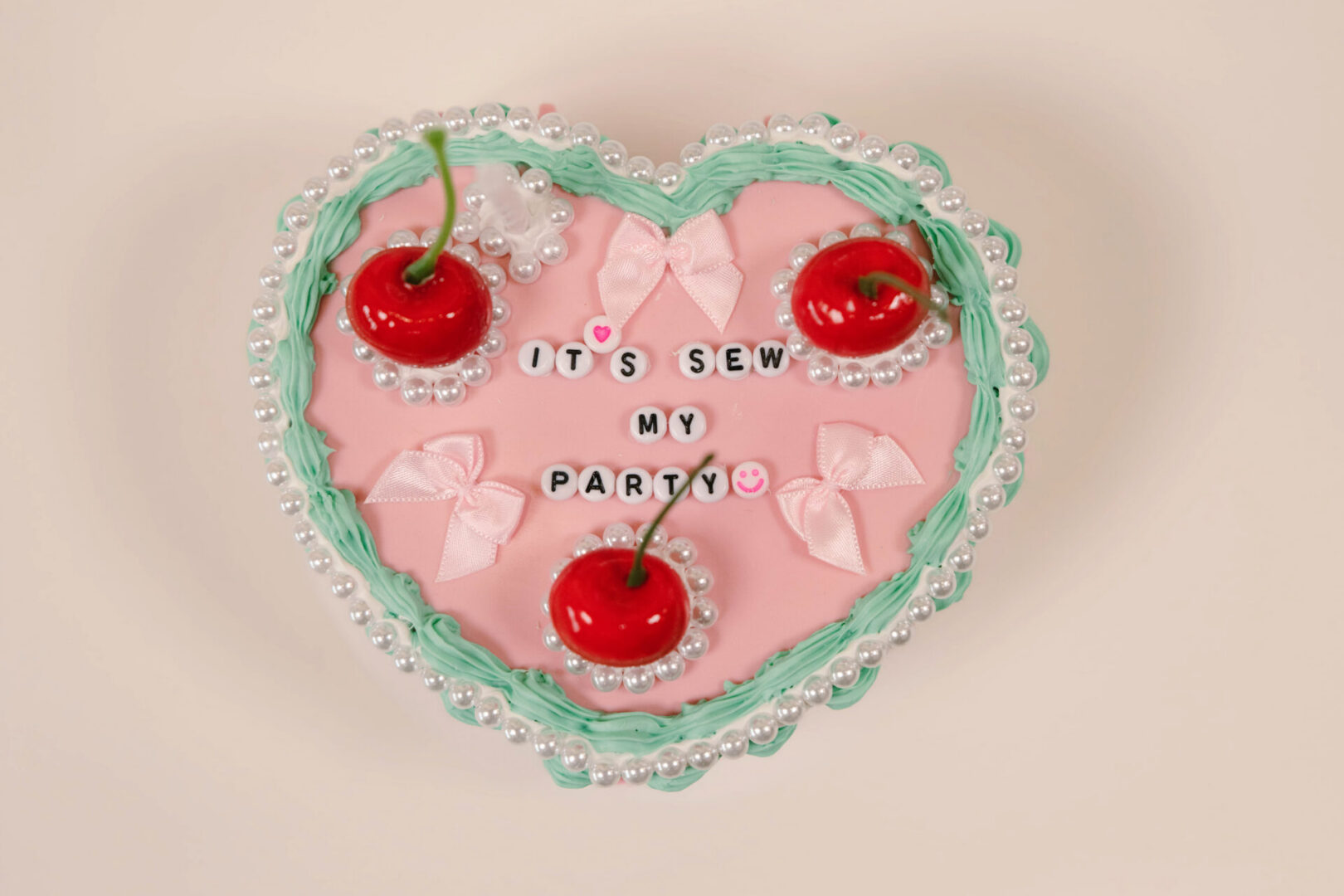 Heart-shaped cake with cherries and text decoration.