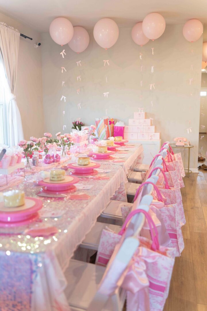 Pink-themed party table with balloons and decorations.