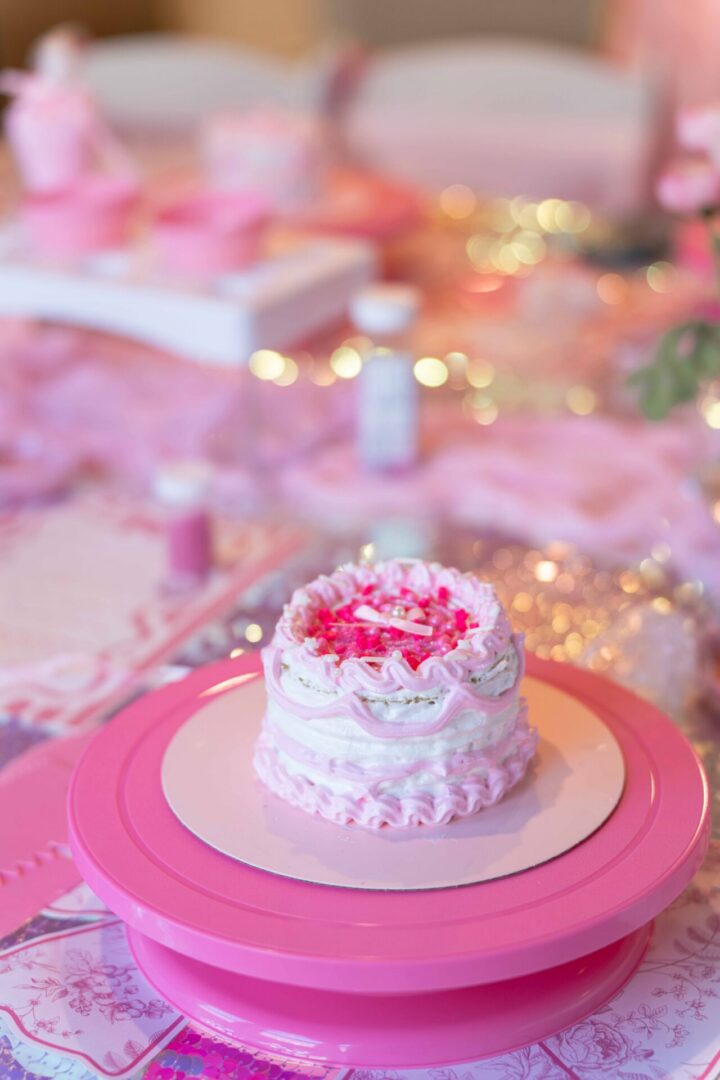 Pink frosted cake on a pink stand.