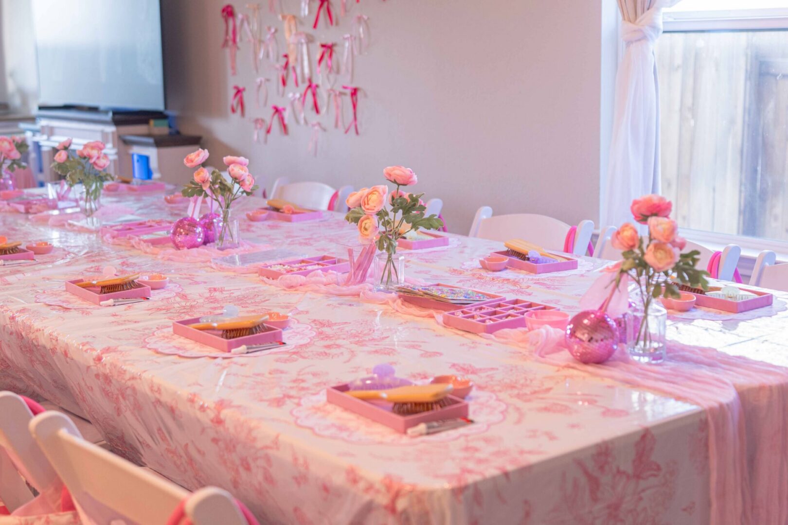 Pink-themed party table with floral decorations.