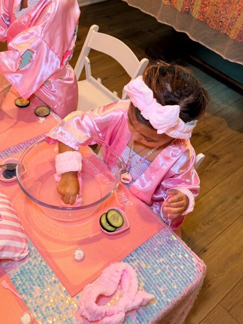 Child in pink robe at spa party.