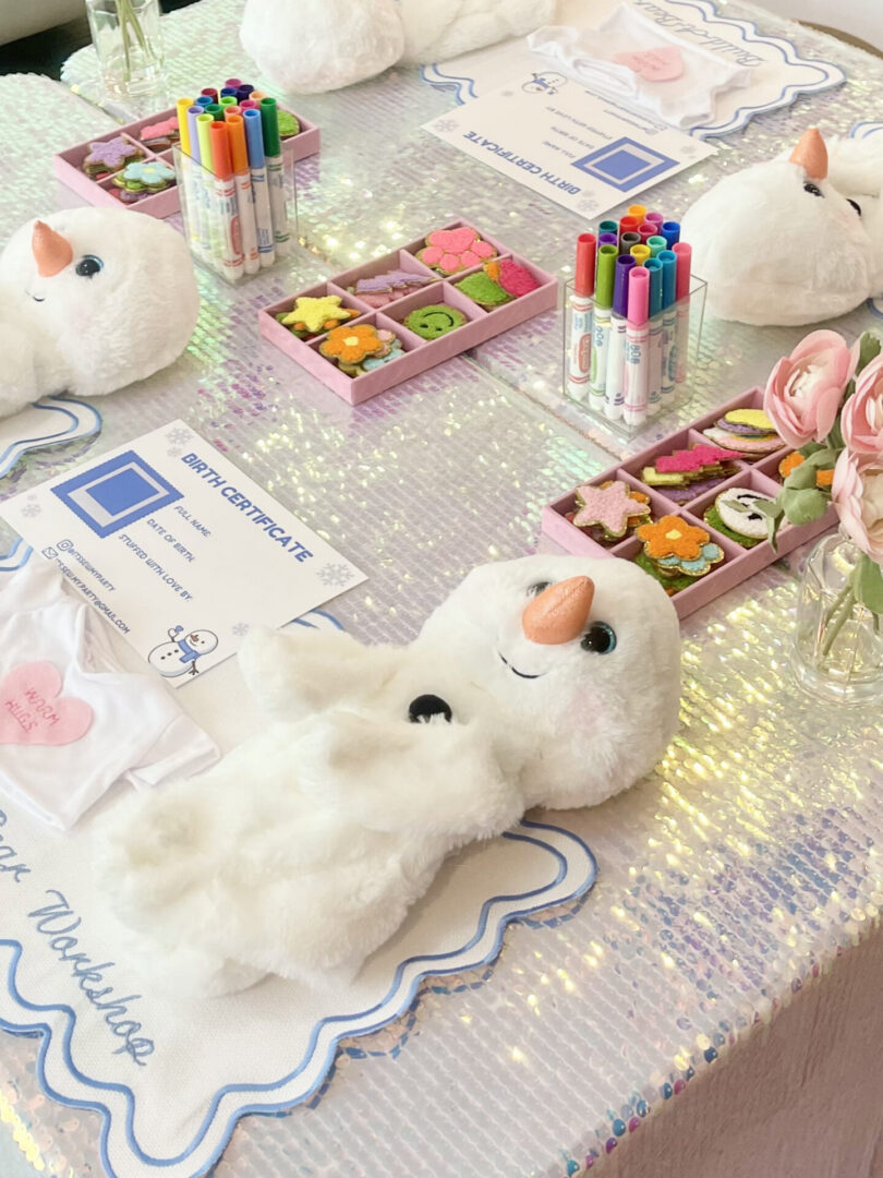 Stuffed snowman toys on a decorated table.