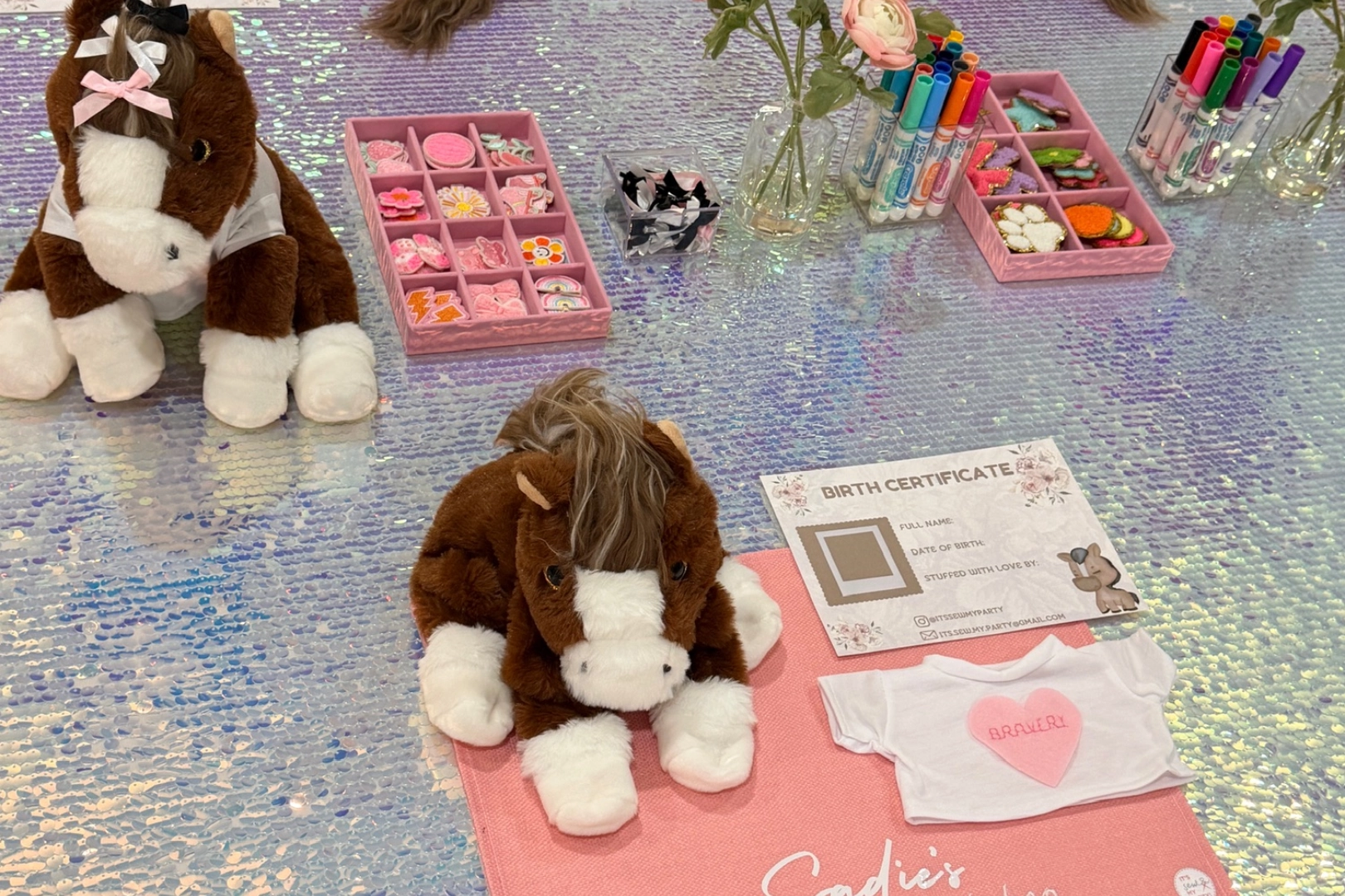 Stuffed horses and crafting supplies on table.