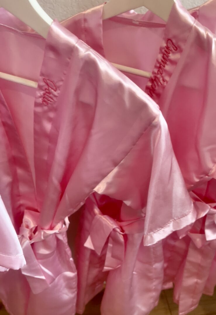 Pink silk robes hanging on hangers.