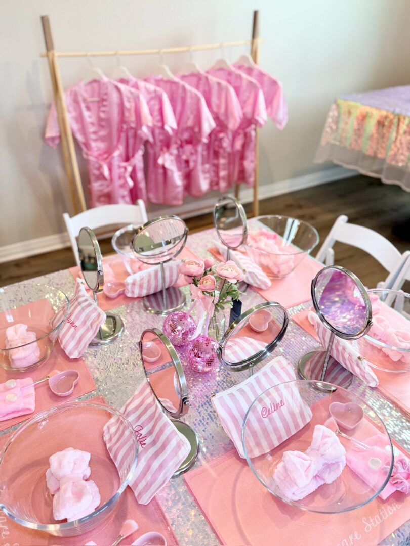 Pink-themed party table with robes and mirrors.