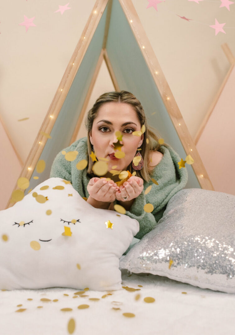 Woman blowing confetti in cozy tent.