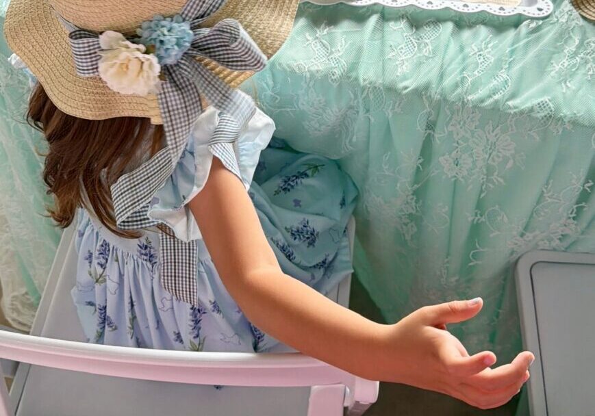 Child in hat at tea party table.
