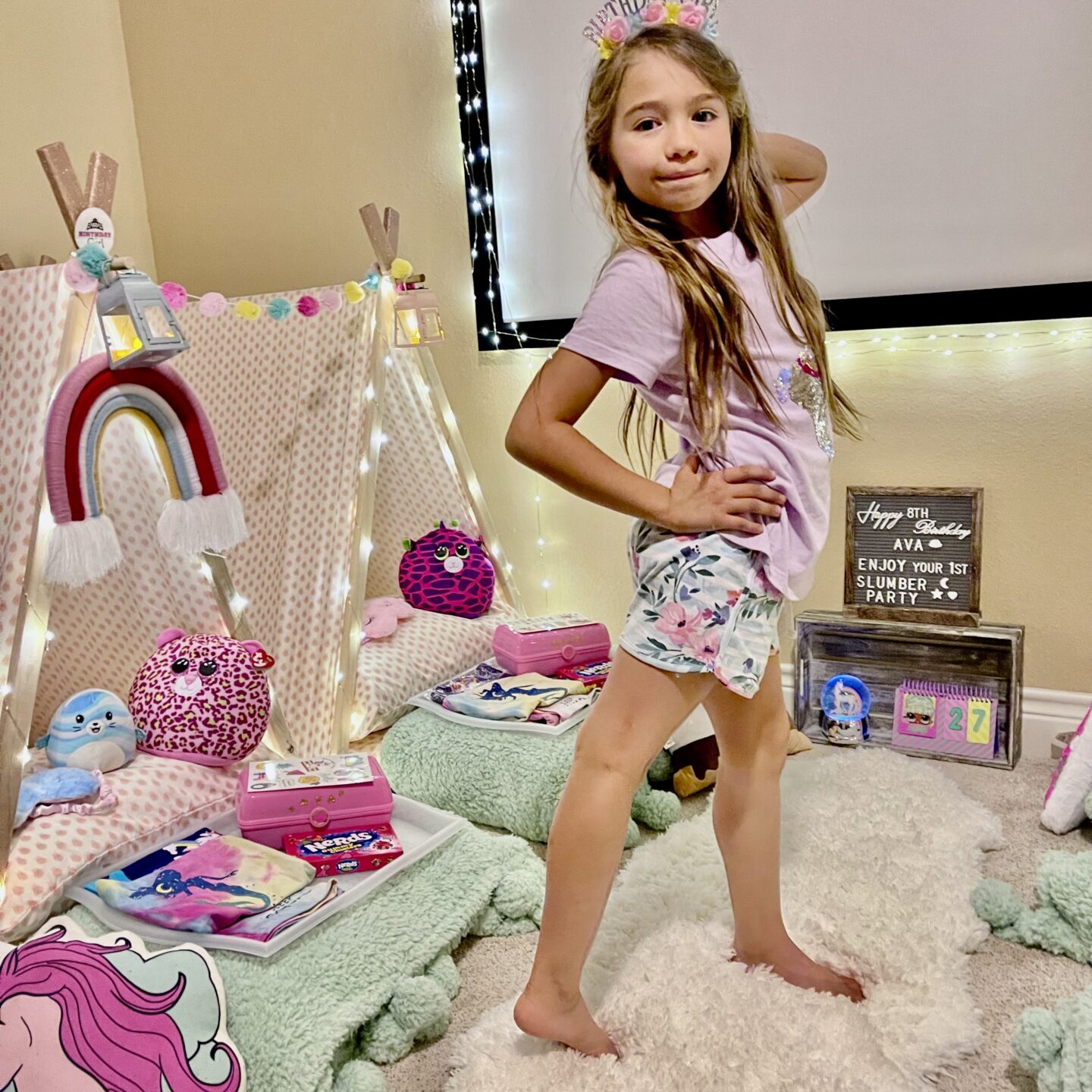 Little girl standing in front of a teepee in a room decorated for her first birthday